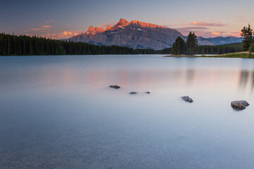 Rundle Mountain reflecting in Two Jack Lake in Banff National Park at sunrise.