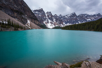 Beautiful turquoise waters of the Moraine lake with snow-covered peaks above it in Banff National Park of Canada