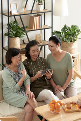 Fototapeta premium Senior female friends watching funny videos on smartphone at home