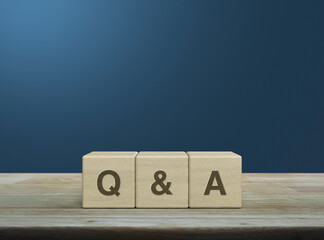 Q and A acronym on wood block cubes on wooden table over light blue gradient background, Frequently...