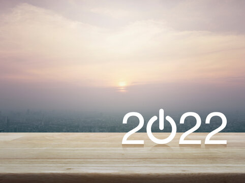 2022 start up business flat icon on wooden table over modern city tower and skyscraper at sunset, vintage style, Happy new year 2022 cover concept © grapestock
