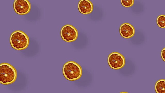 Colorful pattern of dried grapefruit slices on purple background with shadows. Seamless pattern with dried grapefruit chips. Realistic animation. 4K video motion