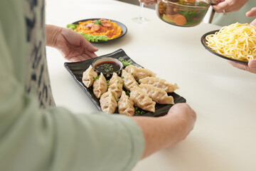 Hands of senior women putting plates with delicious dishes on dinner table
