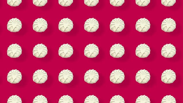 Colorful pattern of white zephyr on red background with shadows. Seamless pattern with zephyr. Marshmallow. Top view. Realistic animation. 4K video motion