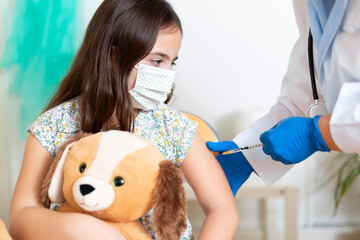 Little Caucasian child being vaccinated against Covid-19 virus. Childhood vaccination concept.