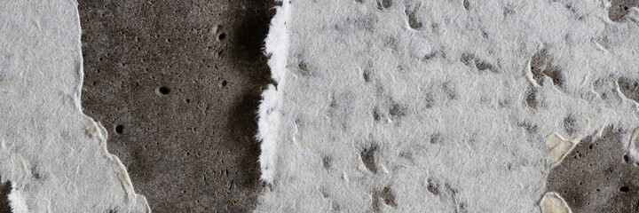 Torn old faded paper wallpaper on a concrete wall. Ragged scraps of white paper on a gray background. Vintage texture for background and design. Closeup view with copy space for text.