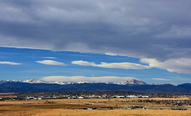 A panoramic view on a sunny day over farmland and the front range of the Colorado Rocky Mountains, as seen from Broomfield, Colorado