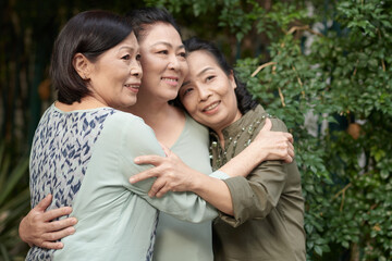 Hugging smiling senior women posing for photo outdoors