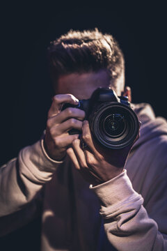 A man photographer with a camera takes a photo in the dark.