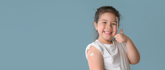 Coronavirus Vaccination Advertisement. Happy Vaccinated Little asian girl Showing Arm With Plaster...