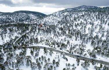 Drone aerial photograph of an asphalt motorway crossing the snowy mountain in winter.