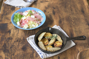 食卓の上の、スキレットの上の焼き野菜と、生ハムチーズサラダ