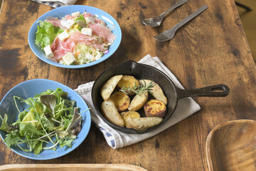 食卓の上のスキレットの焼き野菜と、生ハムチーズサラダ