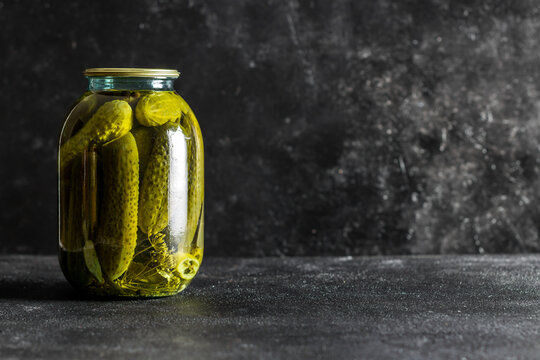 pickled village cucumbers in a jar on a dark background