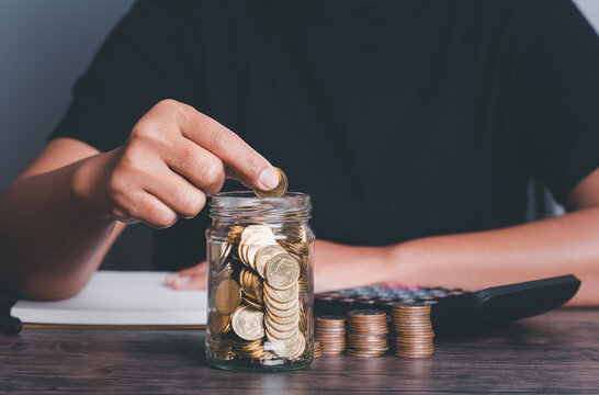 business accounting with saving money with hand putting coins in jug glass concept financial,hand holding coins putting in glass. concept saving money and finance investment vintage picture style.