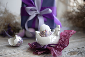 Easter composition with an egg and a gift on a blurred background.