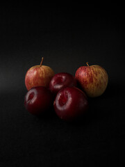 Fresh Plums and Apples isolated on black background. Delicious fruits