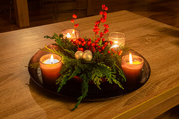 Handmade Christmas decoration consisting of candles, conifer branches and red berries