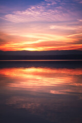 Obraz premium Beautiful colorful sunset sky and forest on the horizon reflecting in the water of the lake