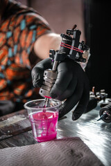 Hand of tattoo artist with a tattoo gun.