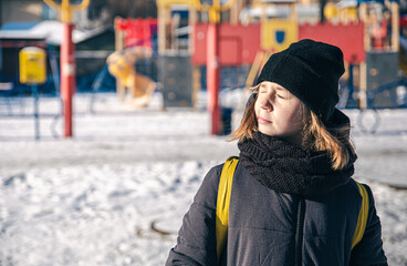 A little girl is heated in the sun in cold winter weather.