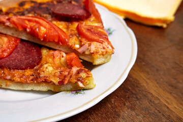 Pieces of pepperoni pizza on a white plate close up