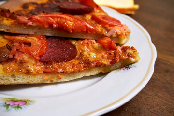Pieces of pepperoni pizza on a white plate close up side view