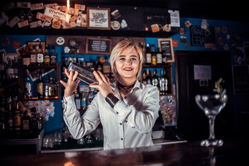 Experienced girl bartending demonstrates his skills over the counter while standing near the bar counter in bar