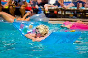 Tween girl relaxing on the inflatable ring in resort pool 