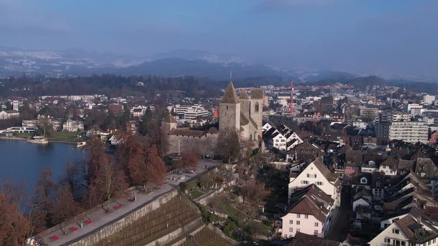 Mighty medieval fortress over roman old town Rapperswil, aerial orbit.