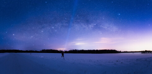 Milky Way Arc and sky full of stars above the snow field and a man with flashlight pointing in the sky © Sergey Egorov