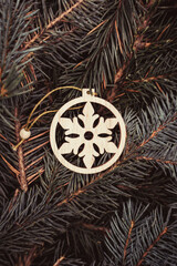
Christmas toy, wooden snowflake, on the branches of a Christmas tree, photo indoors with light