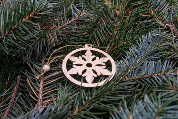 
Christmas toy, wooden snowflake, on the branches of a Christmas tree, photo indoors with light