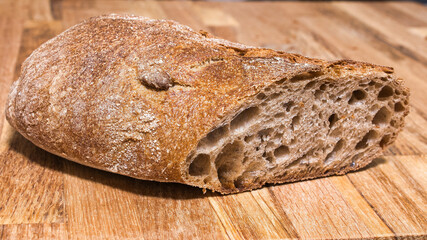Cut loaf of bread on a wooden cutting board.