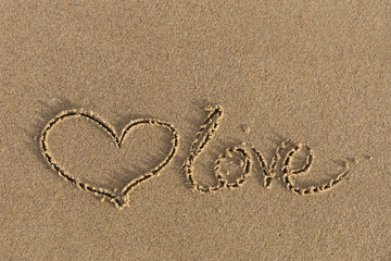Heart drawn in the sand with the inscription love.
