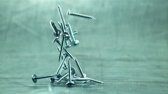 Screws fall on the table. On a gray background. Filmed is slow motion 1000 frames per second. High quality FullHD footage