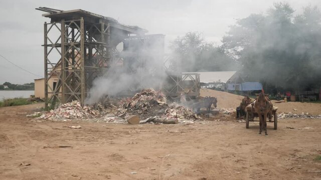 burning plastics and garbage with empty horse carts waiting on the side