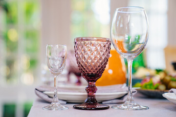 a shot, wine glass of white transparent and of colored glass on the table.