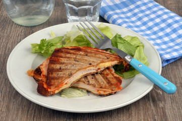 Croque-monsieur coupé en deux servi dans une assiette avec de la salade