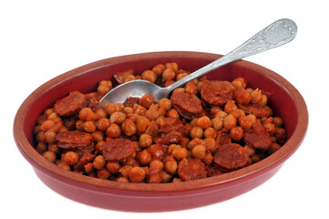 Plat de pois chiches et chorizo avec une cuillère en gros plan sur fond blanc