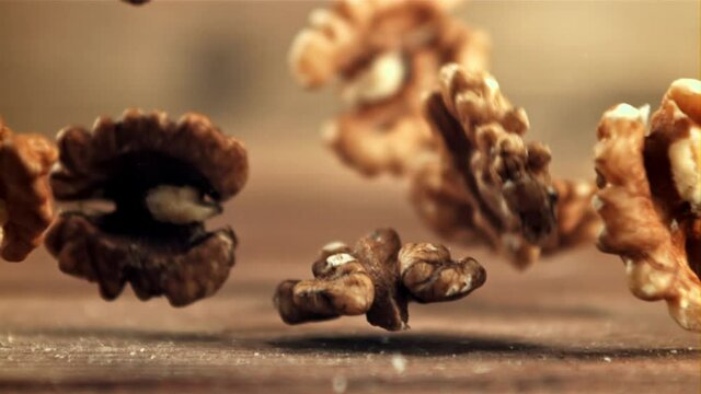 Peeled walnuts fall on the table. On a wooden background. Filmed is slow motion 1000 fps. High quality FullHD footage