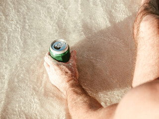 Can of beer and an attractive man on the background of the swim pool. Top view, close-up. Vacation and travel concept. Moments of celebration
