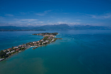 Fototapeta na wymiar Aerial view of the island of Sirmione. Sirmione, Lake Garda, Italy. Panorama of Lake Garda. Castle on the water in Italy. Peninsula on a mountain lake in the background of the alps.