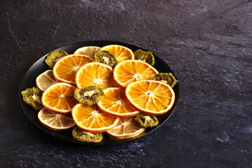 dried slices of orange, lemon, kiwi on a dark background