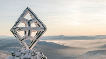 Metal rhombus at the top of the ski resort against the backdrop of beautiful snow-capped mountains