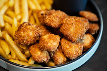 nuggets with french fries in a bowl. fast food. delicious and harmful fried food