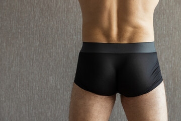 Black underpants are worn on a young man, rear view