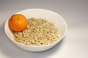 Oatmeal with tangerine. In a white bowl.