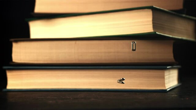 The metal letters of the English alphabet fall on the table. On a black background. Filmed is slow motion 1000 frames per second.
