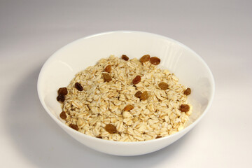 Oatmeal with tangerine slices and raisins. In a white bowl.